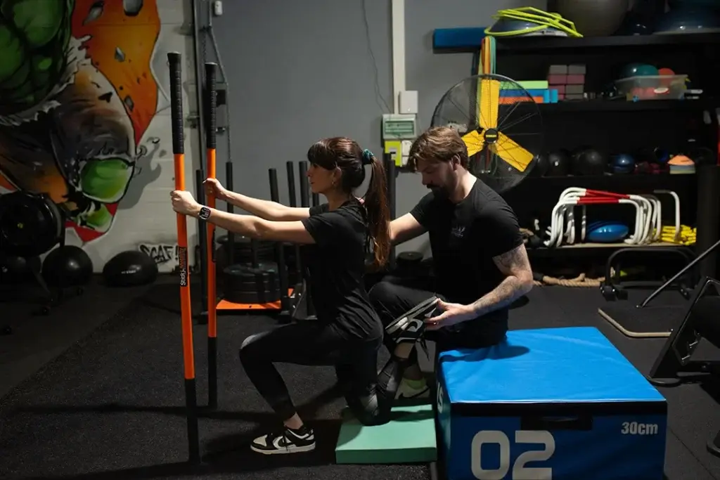 Coach guidant une adhérente pendant un exercice de renforcement musculaire