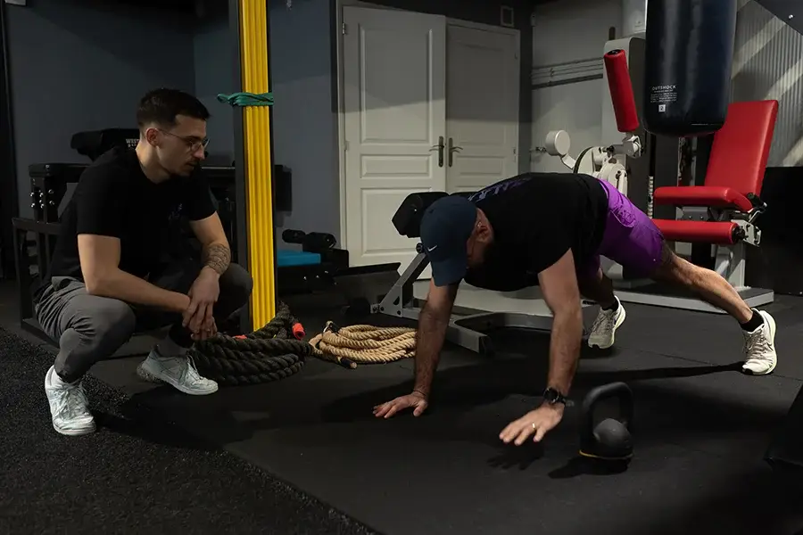 Coach accompagnant un adhérent lors d’un exercice de renforcement musculaire